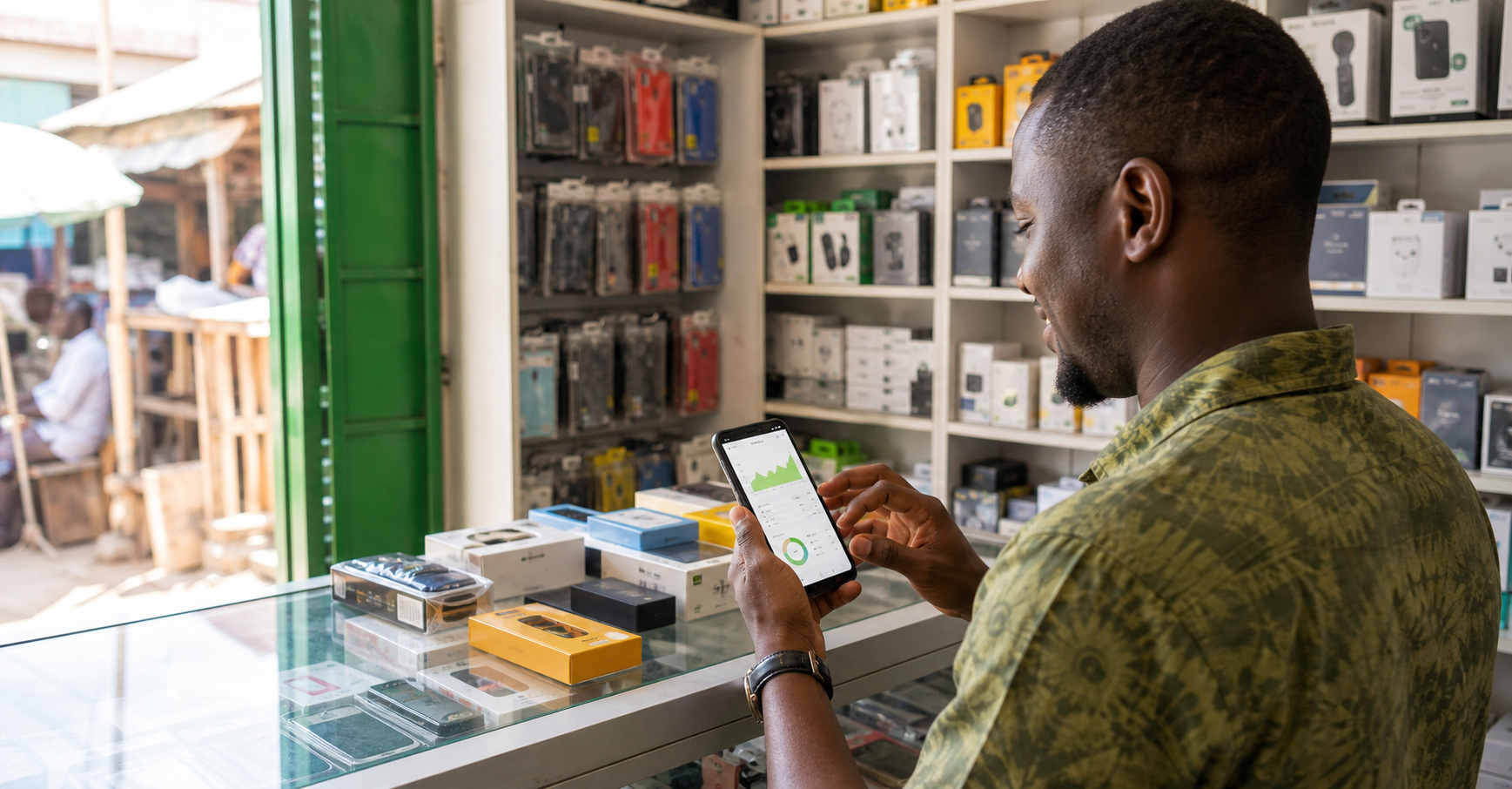 Shop owner checking sales and inventory from a phone in a small electronics shop